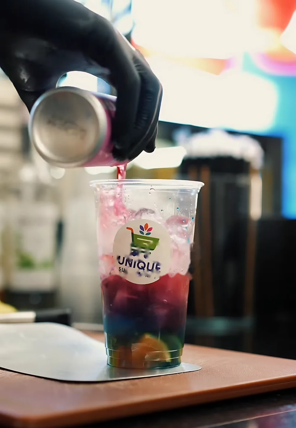 Een koud drankje wordt ingeschonken in een beker met het Unique-logo